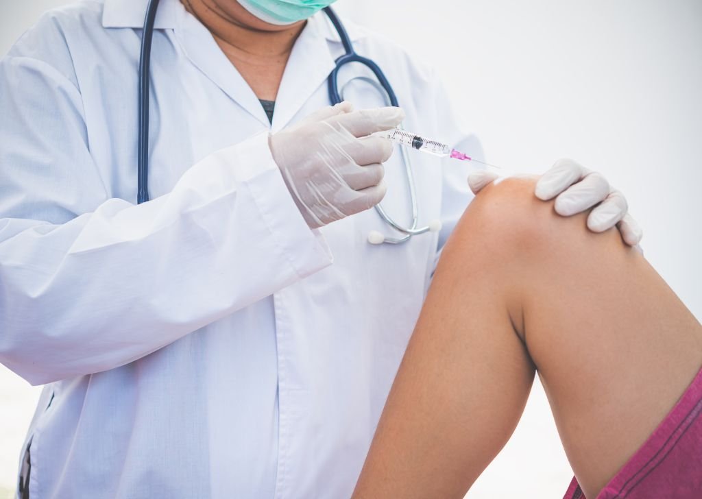 A doctor administering an intra articular injection onto a patient's knee.