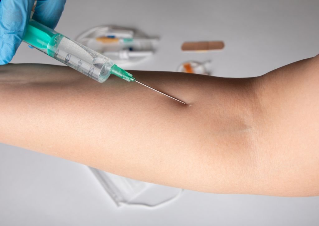 A doctor administering a dose of intra articular injection into a patient's elbow joint.