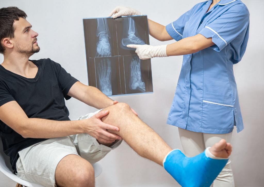 An athlete experiencing joint pain getting treatment with a doctor showing his x-ray.
